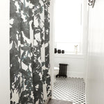 A bathroom with black and white subway tiles and a shower curtain in an abstract black and white botanical print.