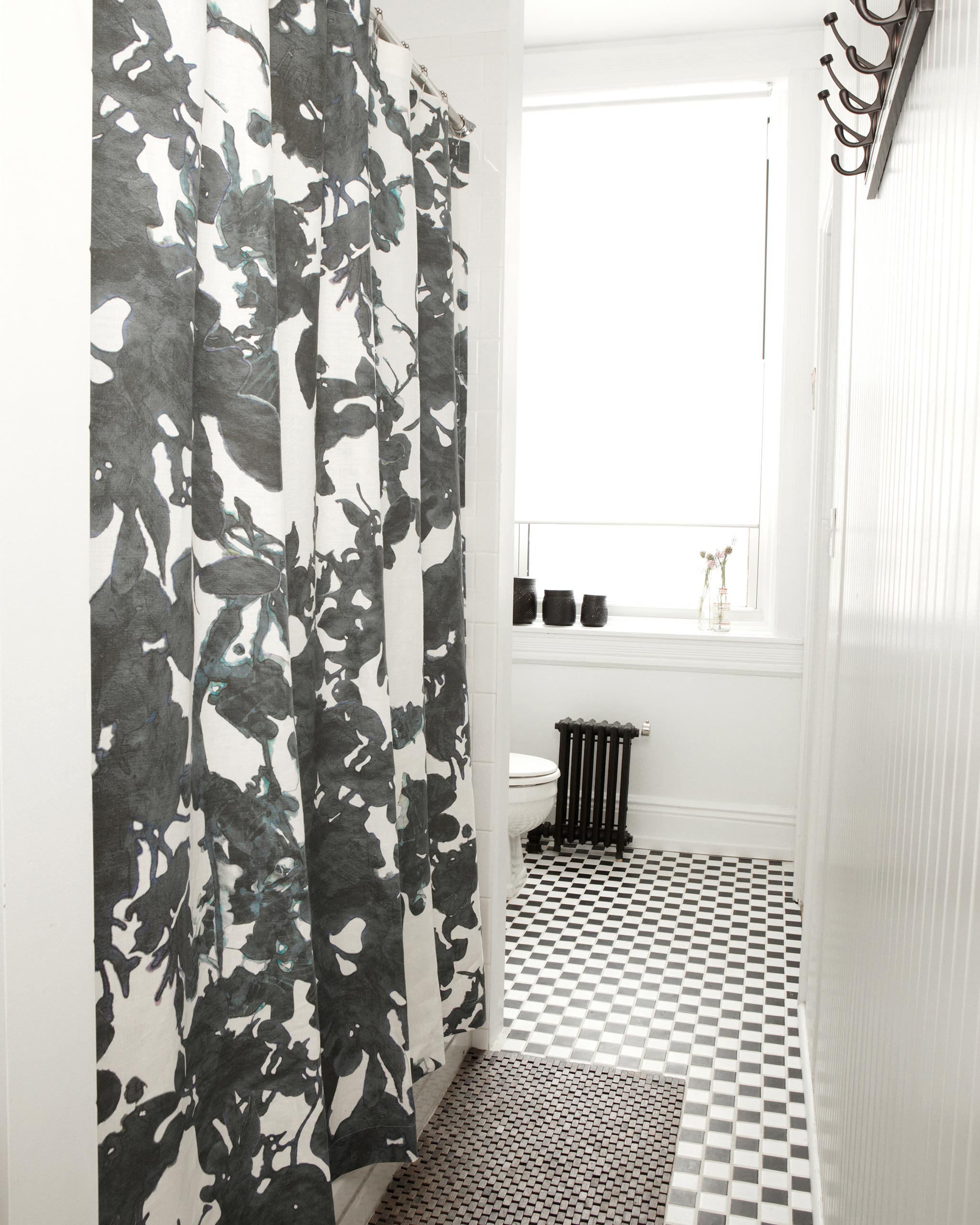 A bathroom with black and white subway tiles and a shower curtain in an abstract black and white botanical print.