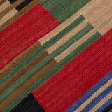 Detail of a handwoven runner in a stacked stripe pattern in blue, red, green , tan and black.