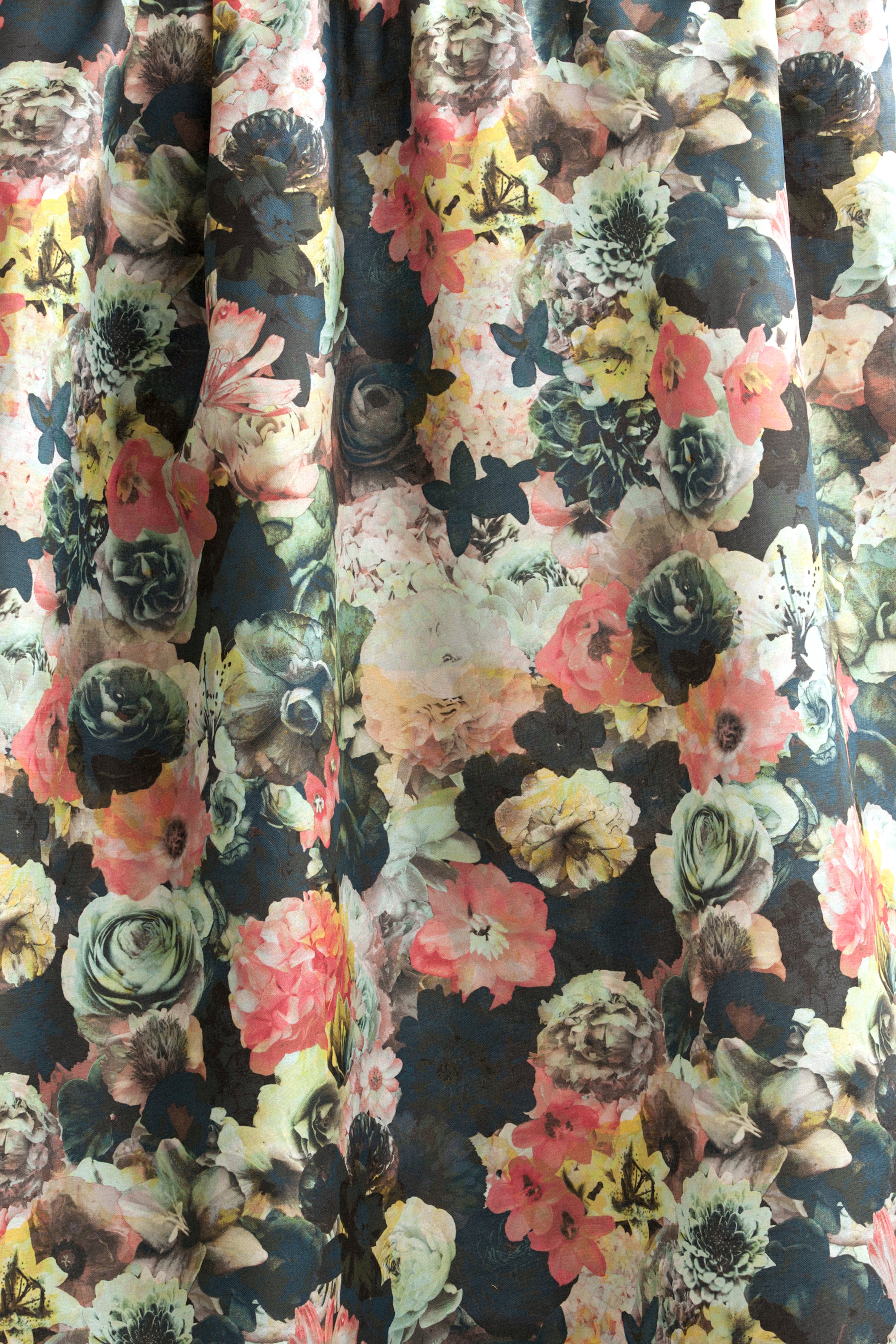 Draped fabric yardage in a dense photorealistic floral print in shades of pink, green and black.