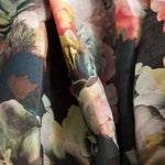 Close-up of draped fabric in a dense photorealistic floral print in shades of pink, green and black.