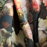 Close-up of draped fabric in a dense photorealistic floral print in shades of pink, green and black.