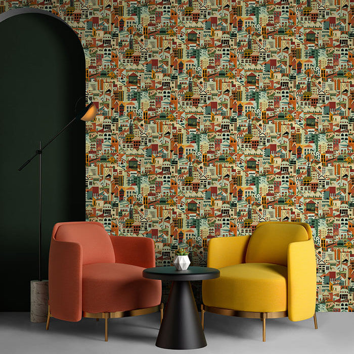 A pair of armchairs in front of a wall papered in a repeating building print in shades of blue, orange, red and green. 