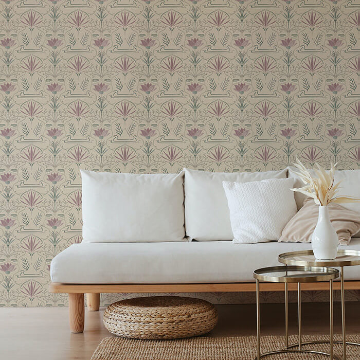 A couch and wooden end table stand in front of a wall papered in an intricate floral lattice print in green, purple and cream.