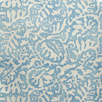 Wallpaper in a botanical paisley print in cream on a light blue field.