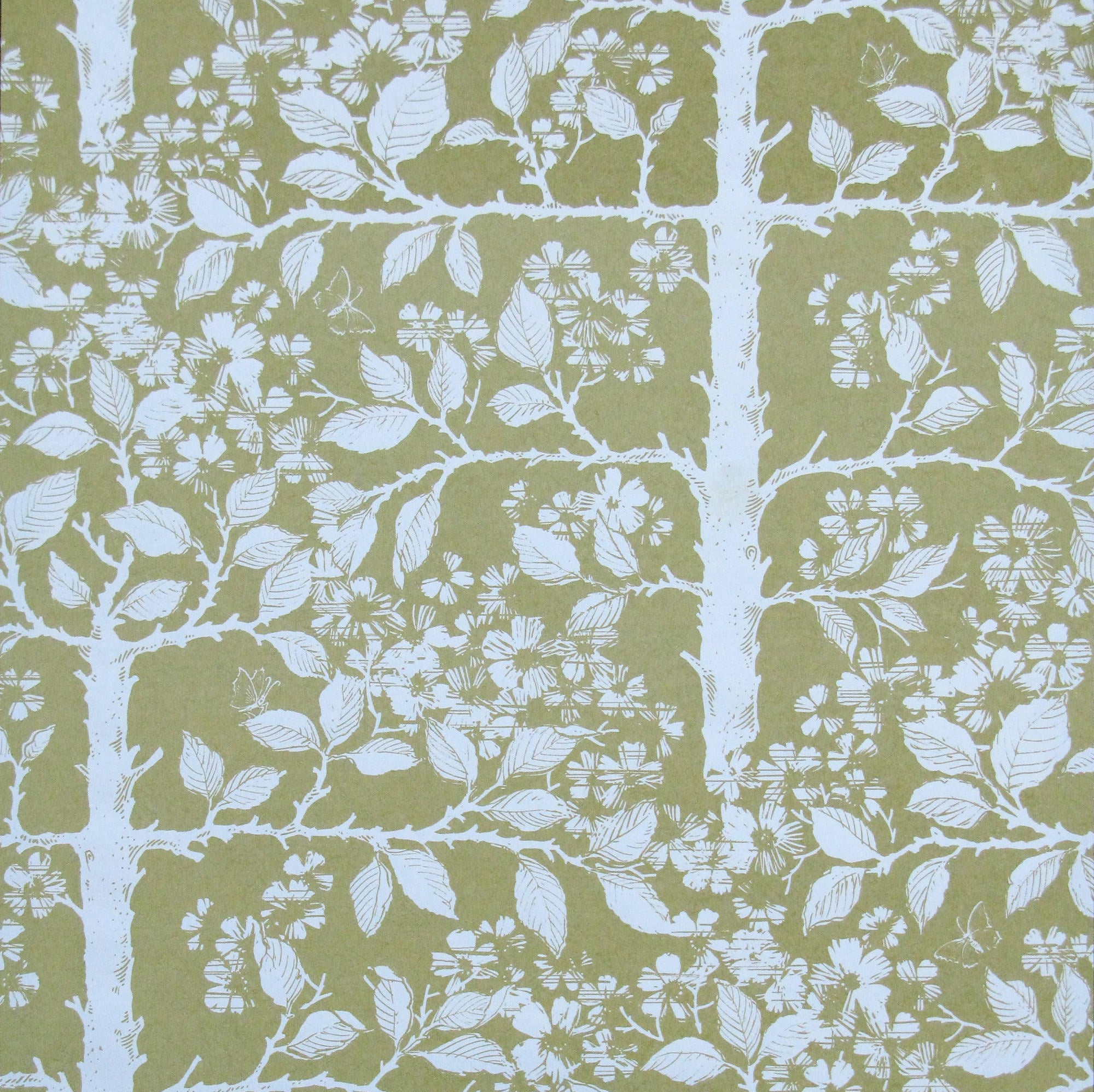 Detail of wallpaper in a large-scale tree and leaf print in white on a light green field.