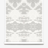 Partially unrolled wallpaper yardage in a painterly ikat print in shades of gray and cream.