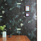 A dining room table stands in front of a wall papered in a playful koi pond print in green, yellow and black.