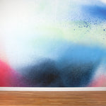 A wall mural in an abstract ombré paint splatter print in shades of blue, navy, red and white.