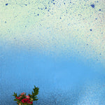 A vase of flowers stands in front of a wall covered in an abstract ombré paint splatter print in blue, navy and green.