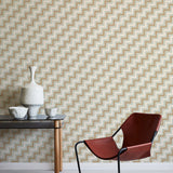 A modernist armchair stands in front of a wall papered in a playful zigzag stripe print in shades of brown, gray and white.