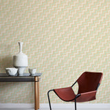 A modernist armchair stands in front of a wall papered in a playful zigzag stripe print in shades of pink, beige and green.