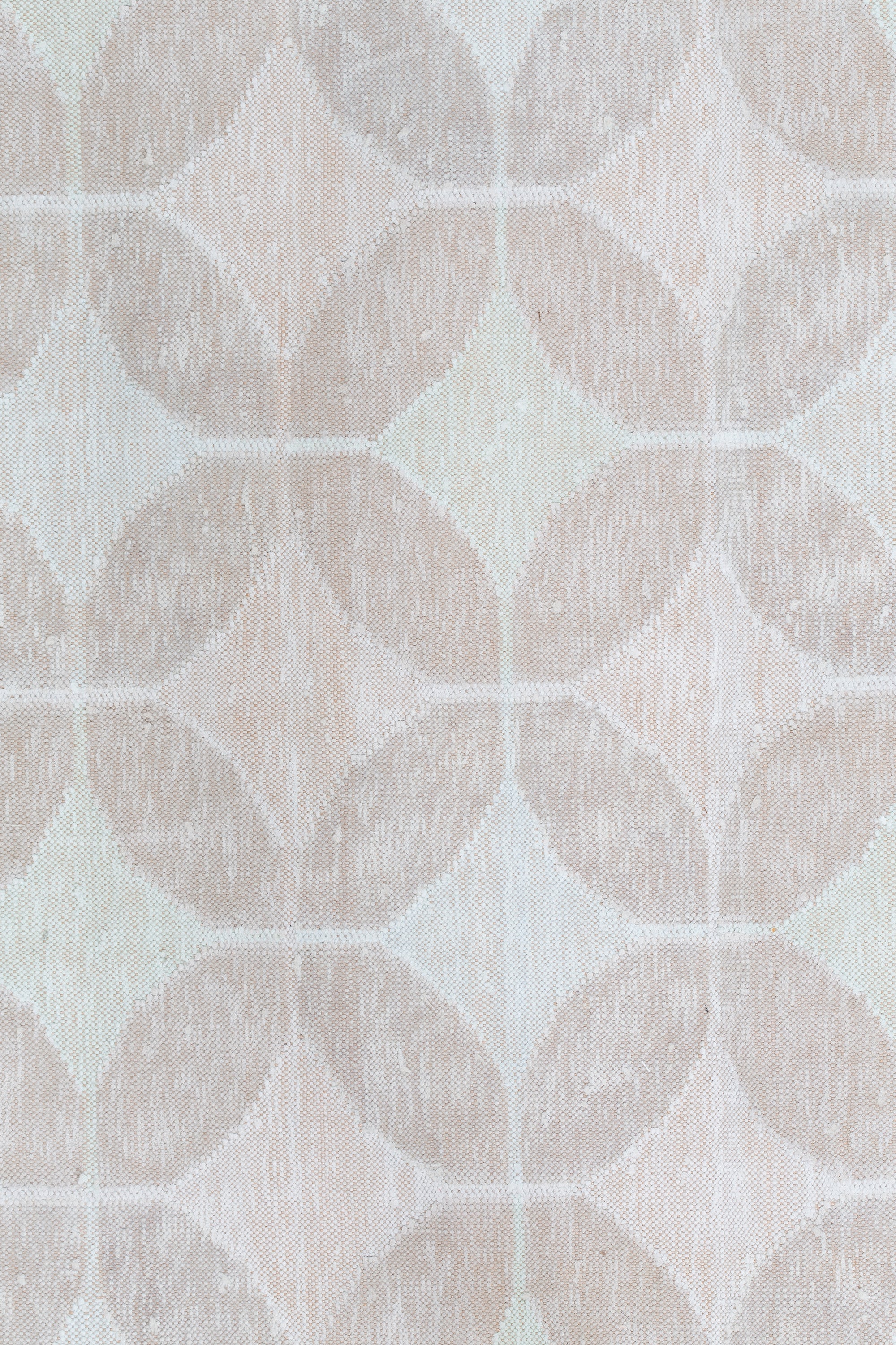 Detail of Alhambra Rug in Stonewash featuring pattern of linked circles that create a star like lattice in a range of pale pink tones a soft white field. 