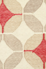 Detail of Alhambra Rug in Tomato featuring pattern of linked circles that create a star like lattice in a range of tan, beige, ecru and bright red on a soft white field. 