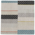 Detail of the Amelia Rug in Camara featuring a minimalist broken stripe pattern, overlayed with thin white diagonal lines. The broken stripes are a mix of black, pale blue and turquoise with accents of red and bright yellow, all on a soft grey field