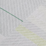 Detail of the Amelia Rug in Peridot featuring a minimalist broken stripe pattern, overlayed with thin white diagonal lines. The broken stripes are a mix of white, grey, and shades of yellow with kelly green accents, all on a light grey field. 