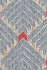 Detail of the Arrow Rug in Powder Blue-Coral features a dense pattern of nesting arrow shapes in soft blue with accents of coral and yellow on an ivory field. 