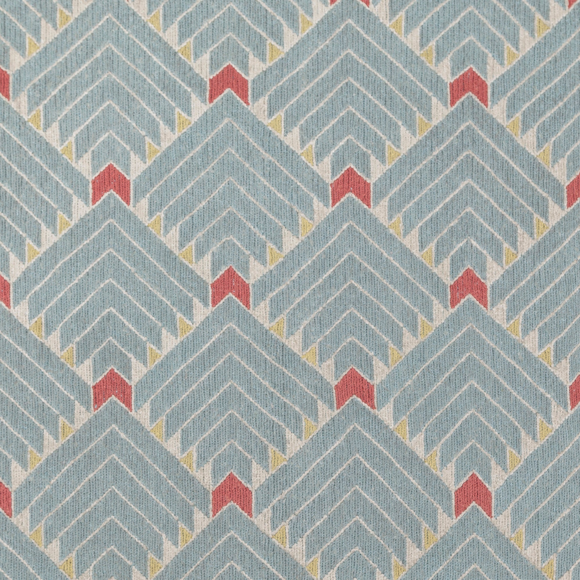 The Arrow Rug in Powder Blue-Coral features a dense pattern of nesting arrow shapes in soft blue with accents of coral and yellow on an ivory field. 