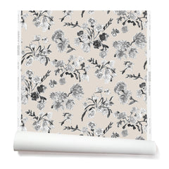 Partially unrolled wallpaper with a pattern of large-scale line-drawn flowers in black ink with gray watercolor, on a beige background.