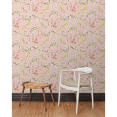 A chair and stool stand in front of a wall papered in large-scale line-drawn flowers in gray ink with red, pink and yellow watercolors, on a pink background.