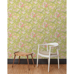 A chair and stool stand in front of a wall papered in large-scale line-drawn flowers in gray ink with red, pink and yellow watercolors, on a light green background.