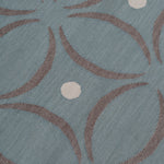 Detail of the Boe rug in Argento, featuring a pattern of curved segments in grey with white circles on a blue field. 