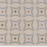 Detail of the Boe rug in Genoa, featuring a pattern of curved segments in light blue and sage green with taupe circles on an ivory field. 