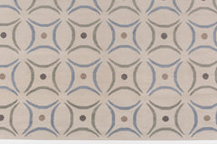 Detail of the Boe rug in Genoa, featuring a pattern of curved segments in light blue and sage green with taupe circles on an ivory field. 