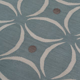 Detail of the Boe rug in Argento, featuring a pattern of white curved segments with taupe circles on a blue field. 
