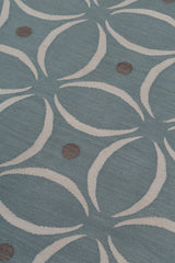 Detail of the Boe rug in Argento, featuring a pattern of white curved segments with taupe circles on a blue field. 