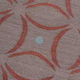 Detail of the Boe rug in Tivoli, featuring a pattern of crimsoncurved segments with light blue circles on a heather purple field. 
