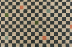 Detail of the Checkerboard Rug in King, a black and tan checkered pattern with random accents of green, sky blue and coral orange. 