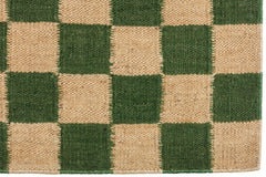 Detail of the Checkerboard Rug in Pawn, a green and tan checkered pattern. 