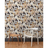 A chair and stool in front of a wall papered in a pattern of many different types of illustrated watercolor dogs with a black background.