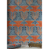 A small bronze filigree box and folded fabric swatch in front of a wallpaper with stamped painted floral motif in red and cobalt on a medium blue background, hover