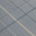 Detail of the Jasper Waffle Rug in Chalcedony, a large scale plaid pattern of denim blue, black, yellow and pale turqouise. 