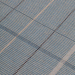 Detail of the Jasper Waffle Rug in Chalcedony, a large scale plaid pattern of denim blue, black, yellow and pale turqouise. 