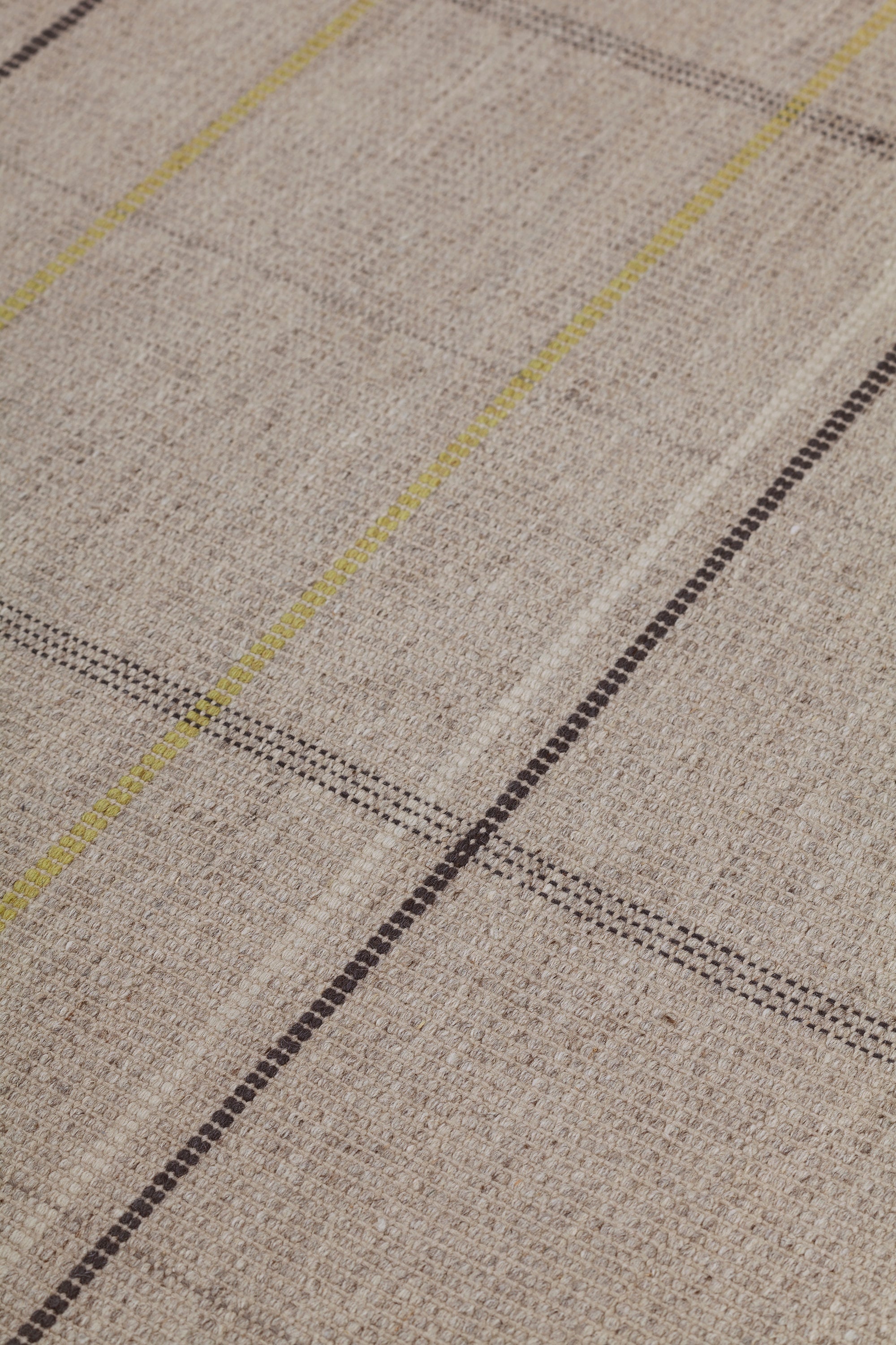 Detail of the Jasper Waffle Rug in Peridot, a large scale plaid pattern of ecru, yellow, grey and off white. 