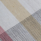 Detail of the Jasper Waffle Rug in Red Fossile, widely spaced stripes of yellow, pink, red, white and black on a split light grey fand ivory field. 