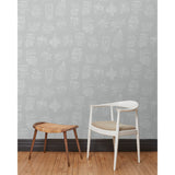 A chair and stool in front of a wall papered in a pattern of white hand-drawn illustrations of New York City landmarks on a gray background.