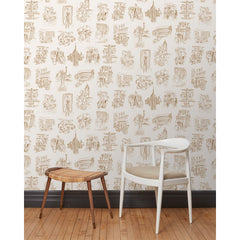 A chair and stool in front of a wall papered in a pattern of sepia tone hand-drawn illustrations of New York City landmarks on a beige background.
