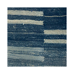 Close-up of a woven wool rug in a mottled navy color with a broken stripe pattern.