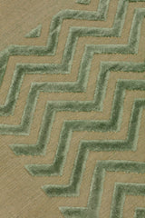 Detail of the Penta Chevron Rug in Pale Jade a light green chevron pattern on a lime green  field with a wide solid border. 