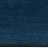 Detail of the Plain Stitched Border Rug in Prussian Blue, a solid indigo rug with a black border with black border with blue and taupe dashes. 