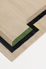 Detail of the Ponti Rug in Salvia, an ivory field with a geometric stair step border in black, with yellow, green and taupe. 