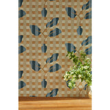 A small white and green floral arrangement at the left edge of the frame against a wallpaper with a complex cornflower and dark blue striped floral motif overlayed a white and tan plaid pattern, hover
