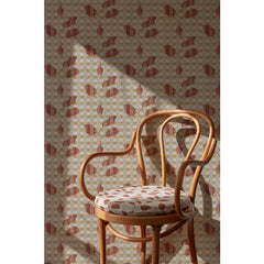 Curved wooden chair with an coral and beige floral cushion in front of a Wallpaper roll with a complex two tone warm red floral motif overlayed a white and tan plaid pattern, 
