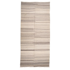 Long rectangular rug in a broken stripe pattern in shades of cream, tan and light brown.