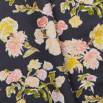 Folded linen swatch with a pattern of large-scale line-drawn flowers in gray ink with red, pink and yellow watercolors, on a black background.