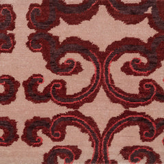 Amped Up rug swatch with a large curlie cue design in shades of  purple and red  on a pale pink field